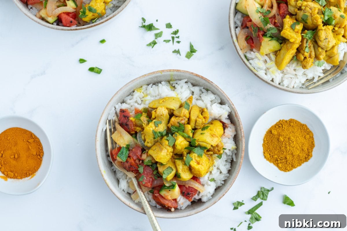 Chicken curry bowls with coconut rice, spiced chicken and a flavorful tomato mixture. Cozy, balanced and perfect for dinner! overhead shot of two servings of chicken curry bowls