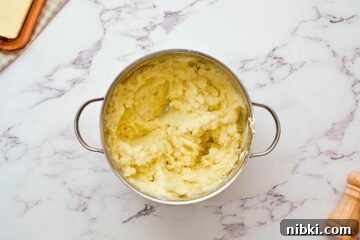 How to Make Perfect Creamy Homemade Mashed Potatoes 5 Pan with butter, milk, and sour cream folded into mashed potatoes for light and fluffy mashed potatoes.