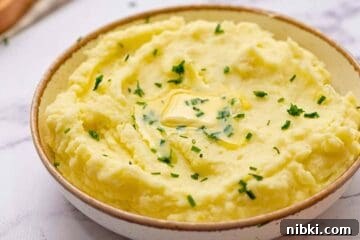How to Make Perfect Creamy Homemade Mashed Potatoes 6 Bowl of creamy gold mashed potatoes topped with butter and chives.