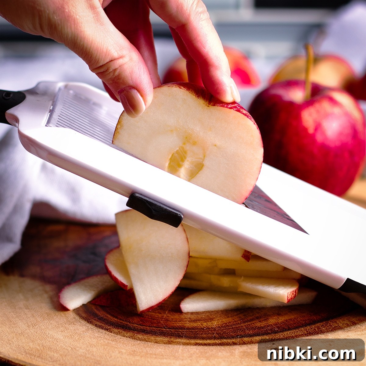 Spiced Apple Cider Cake with Cider Buttercream 11 Someone using a mandolin to slice apples into thin slices.