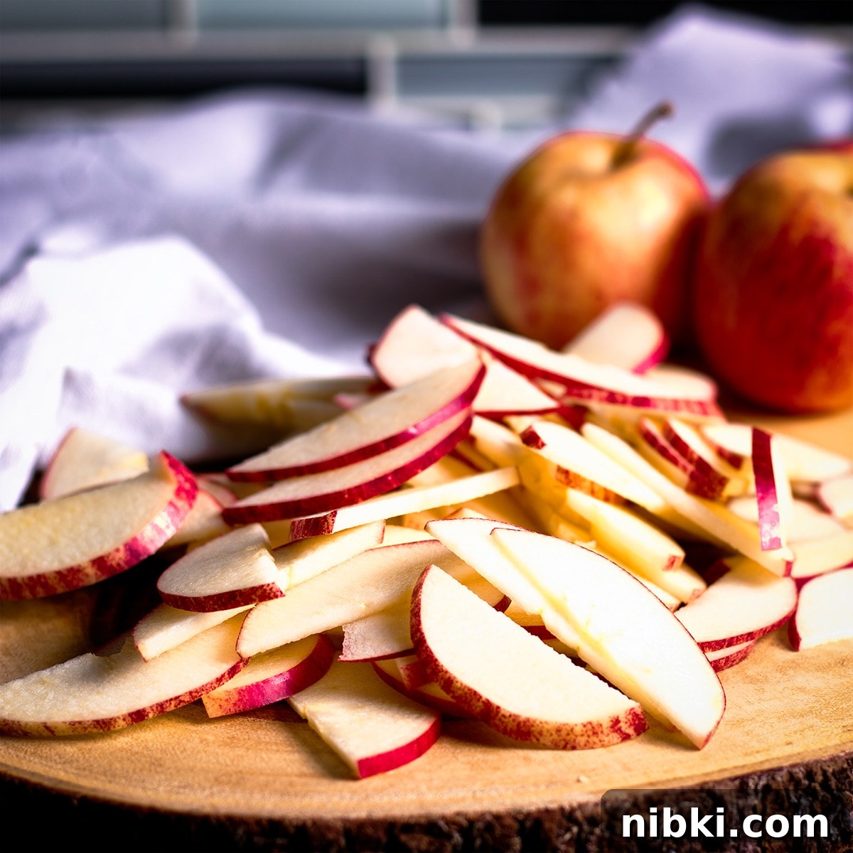 Spiced Apple Cider Cake with Cider Buttercream 12 A pile of apple slices on a wood cutting board.