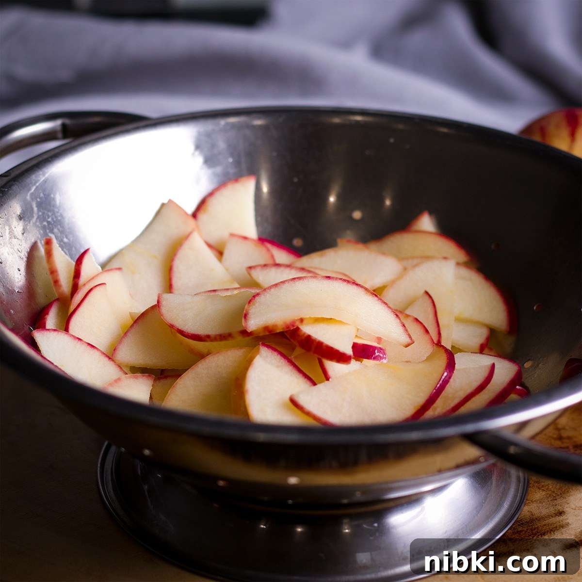 Spiced Apple Cider Cake with Cider Buttercream 13 Apple slices in a metal colander.