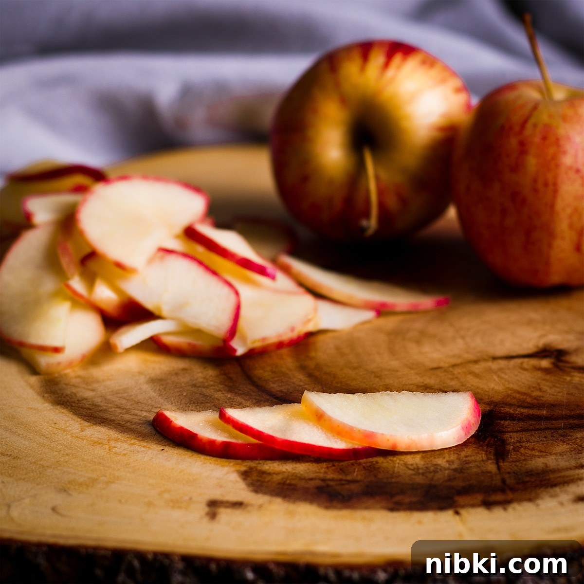 Spiced Apple Cider Cake with Cider Buttercream 14 Three thin apple slices layed out on a wood cutting board.