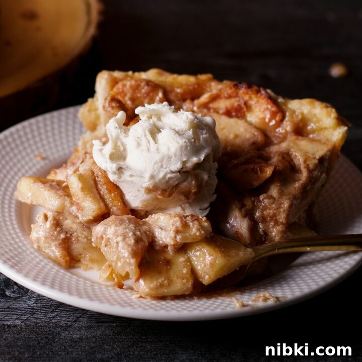 A slice of German Apple Pie topped with a scoop of vanilla ice cream.