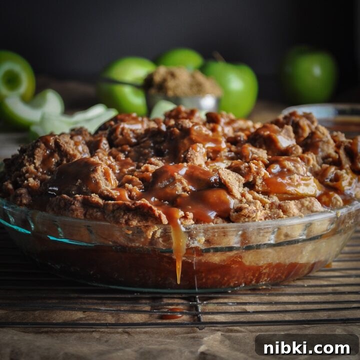 A salted caramel apple pie with crumb topping cooling on a wire rack.