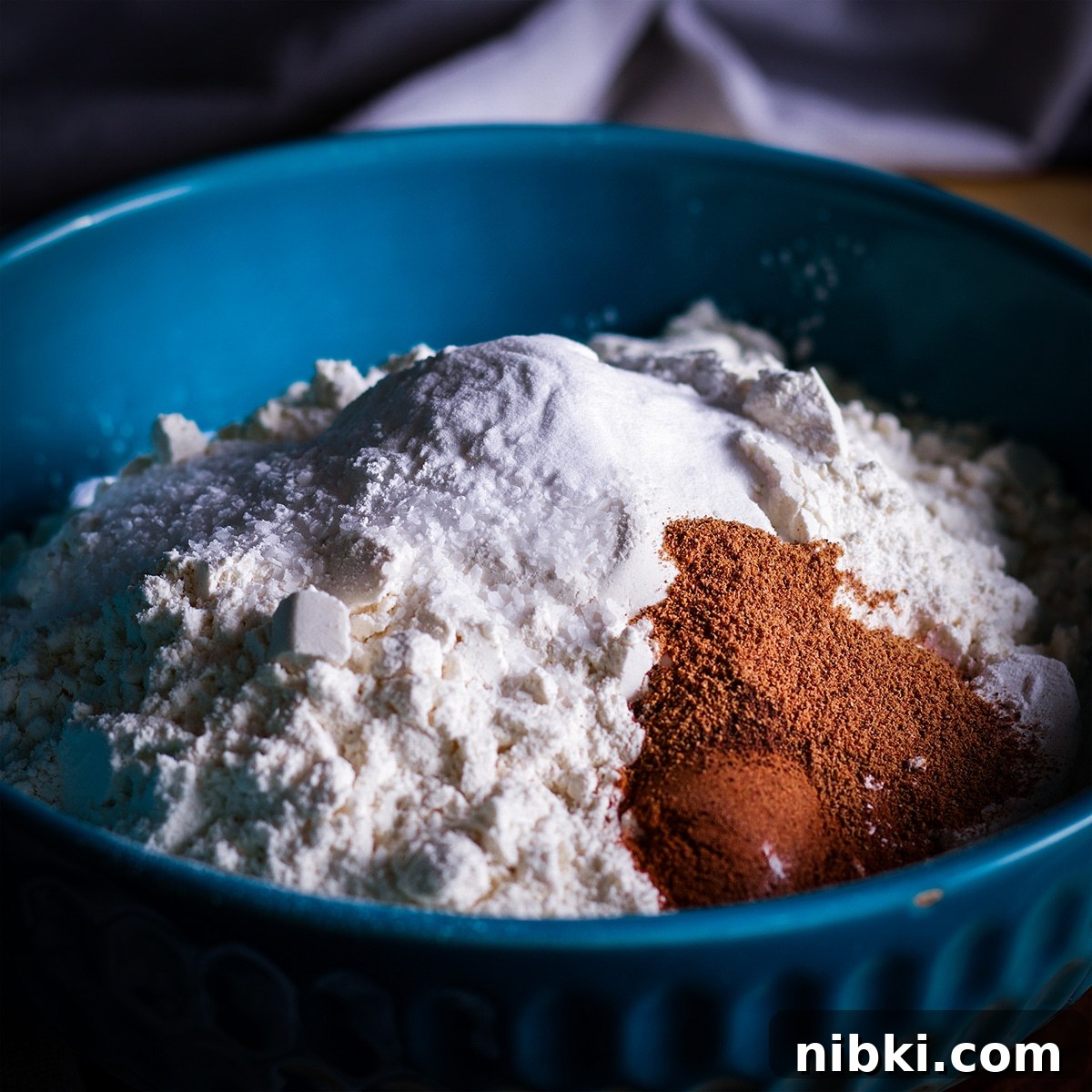 Spiced Apple Cider Cake with Cider Buttercream 4 All of the dry ingredients for apple cider cake in a blue bowl.