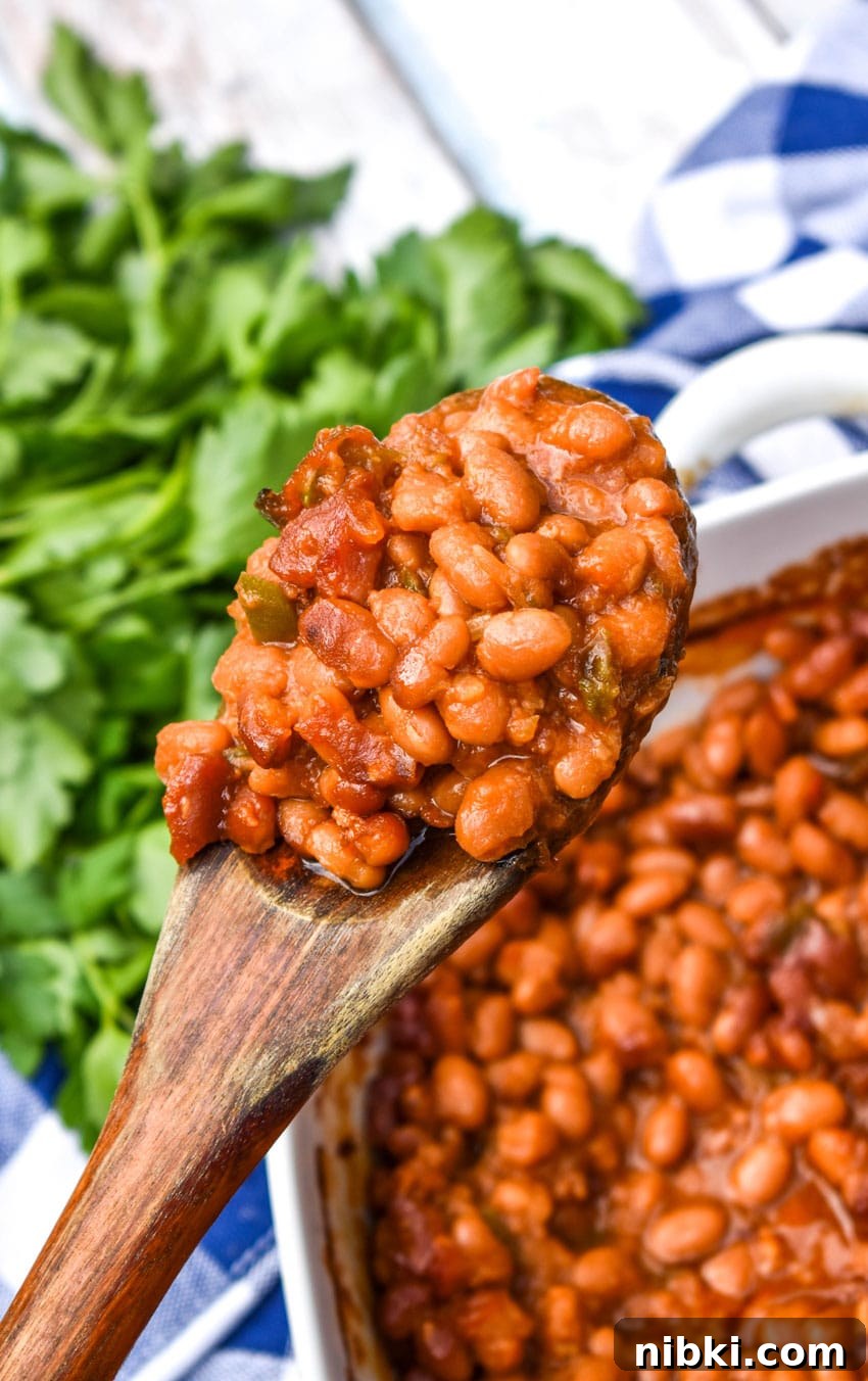 a wooden spoon holding up a scoop of the best canned baked beans recipe