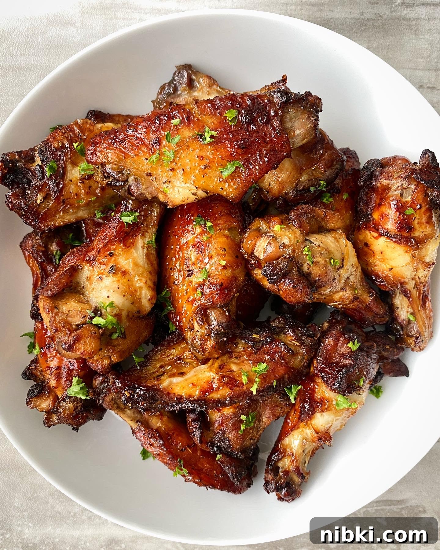 Crispy Marinated Chicken Wings in the Air Fryer 9 cooked marinated air fryer chicken garnished with parsley in a white bowl