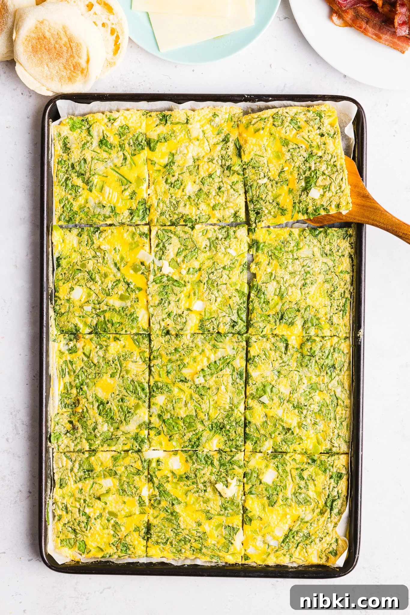 Sheet pan eggs for sandwiches sliced into squares on a sheet pan.