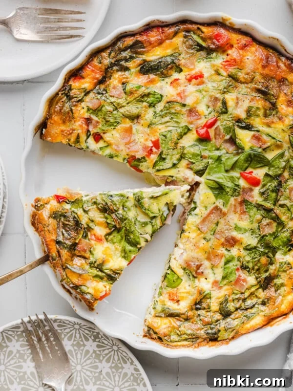 A serving utensil picking up a slice of crustless cottage cheese quiche from the baking dish.
