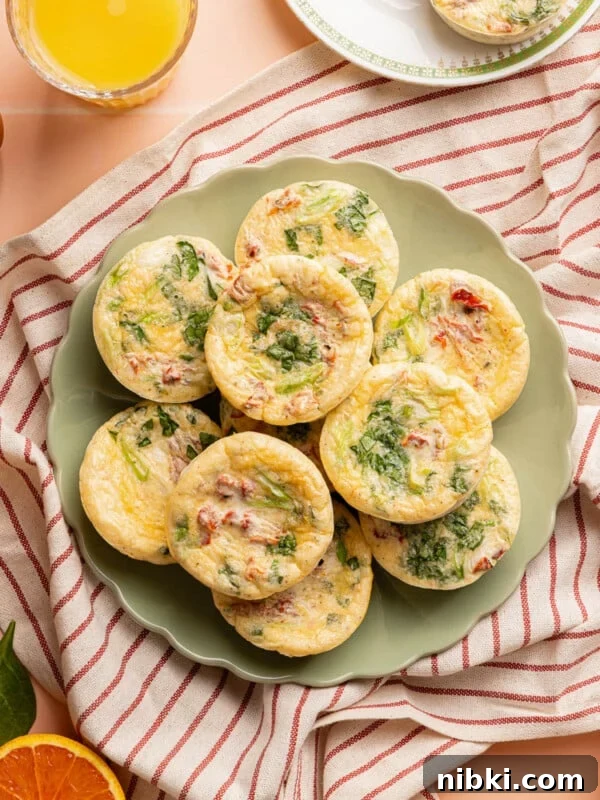 10 roasted red pepper egg white bites sitting on a green plate on top of a red stripped towel on a countertop.