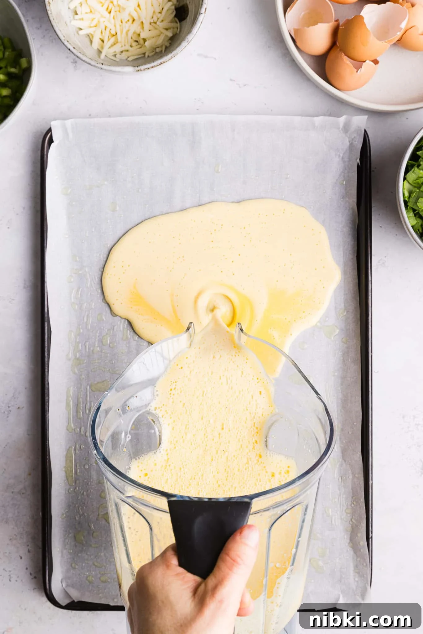 Blended eggs and cottage cheese being poured into a sheet pan.