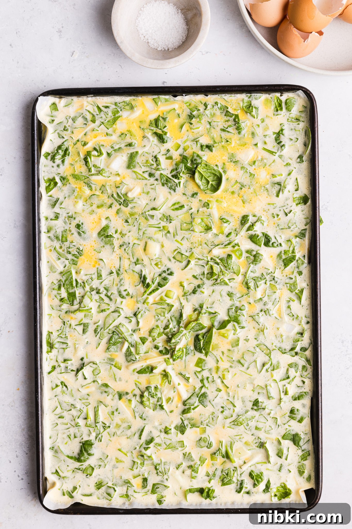 Blended eggs and cottage cheese mixed with veggies in a sheet pan.