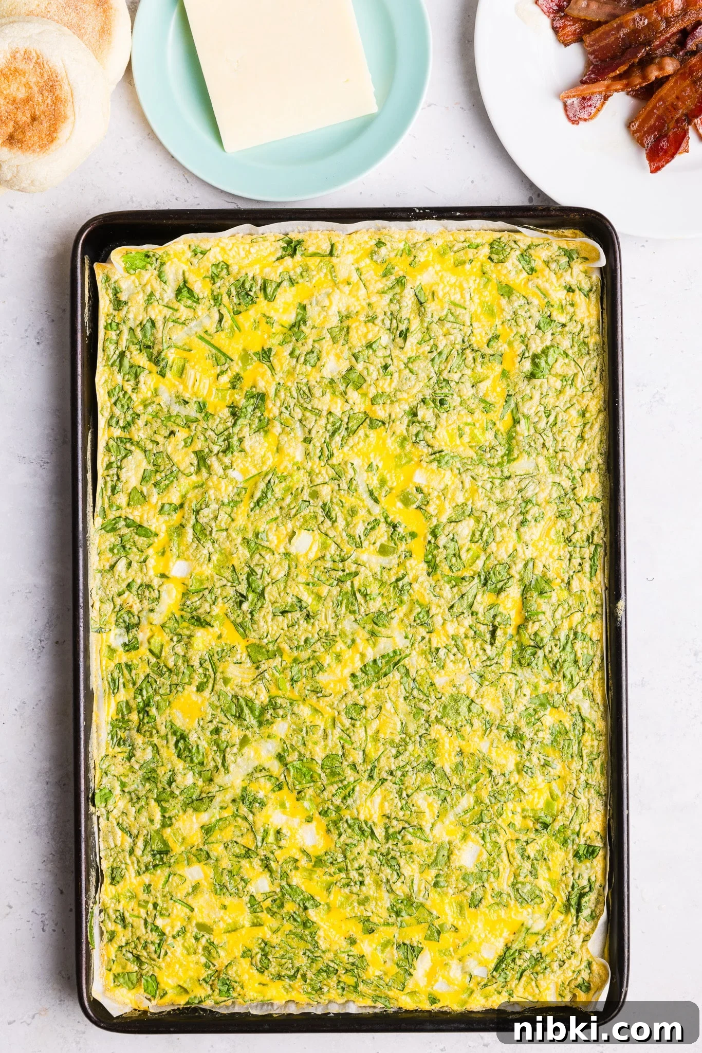 A sheet pan of baked eggs with veggies.
