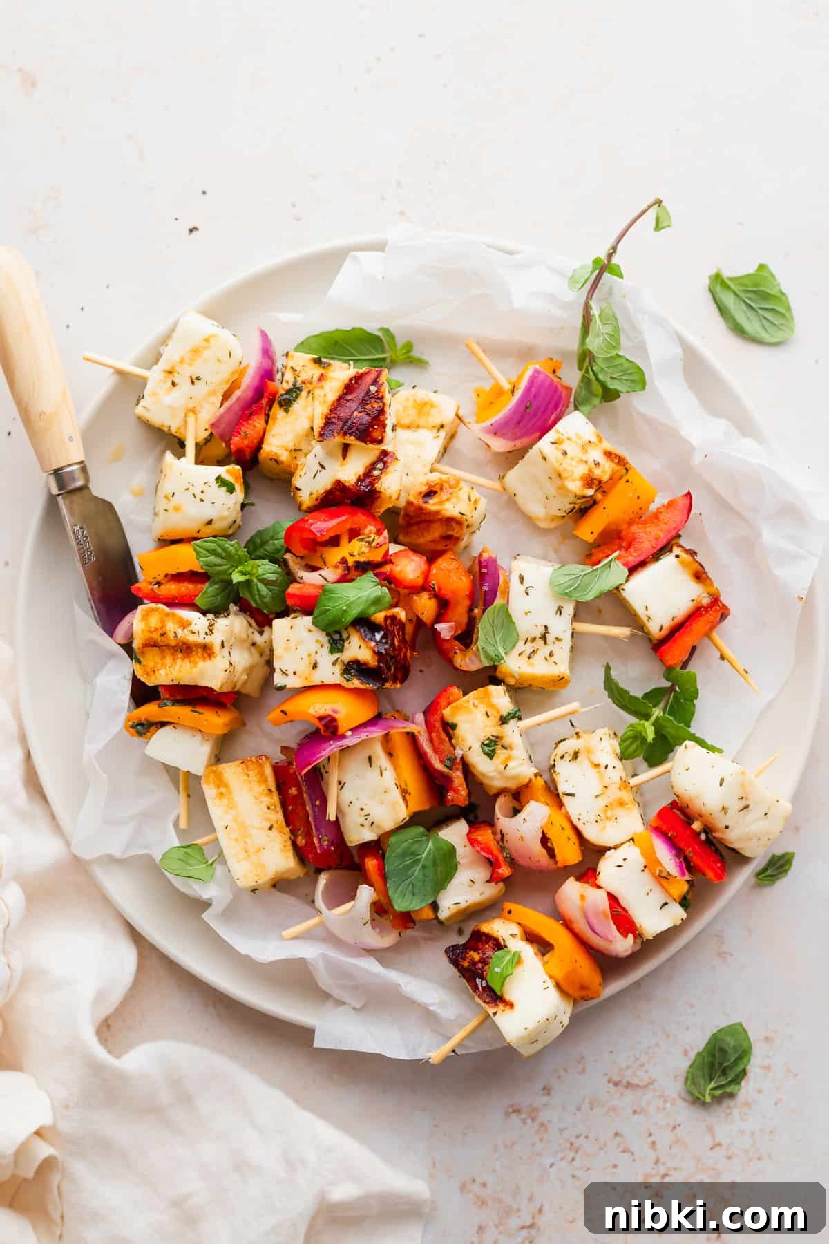 These sweet and savory Grilled Halloumi Skewers bring together deliciously marinated halloumi and veggies for a delightfully bright summer dish. grilled halloumi skewers on a plate