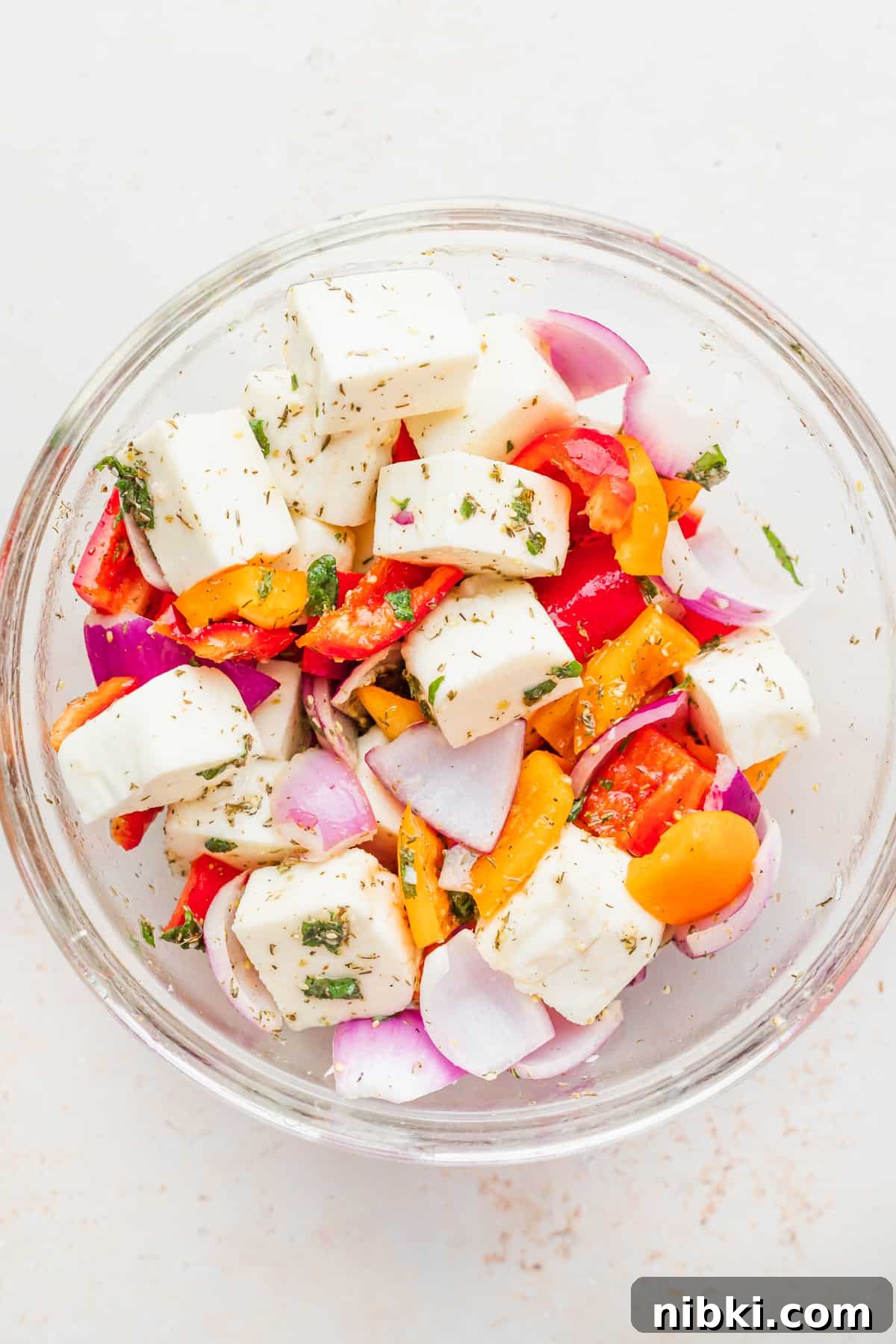 These sweet and savory Grilled Halloumi Skewers bring together deliciously marinated halloumi and veggies for a delightfully bright summer dish. grilled halloumi skewers ingredients in a bowl
