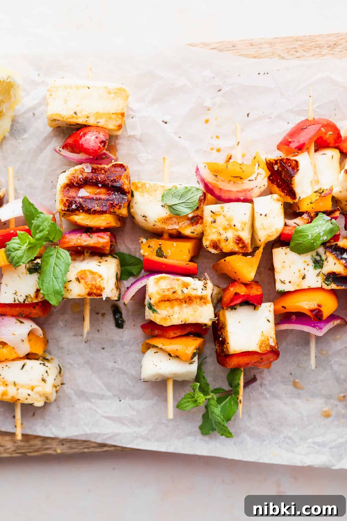 These sweet and savory Grilled Halloumi Skewers bring together deliciously marinated halloumi and veggies for a delightfully bright summer dish. grilled halloumi skewers in a close up photo that highlights the bright vegetables