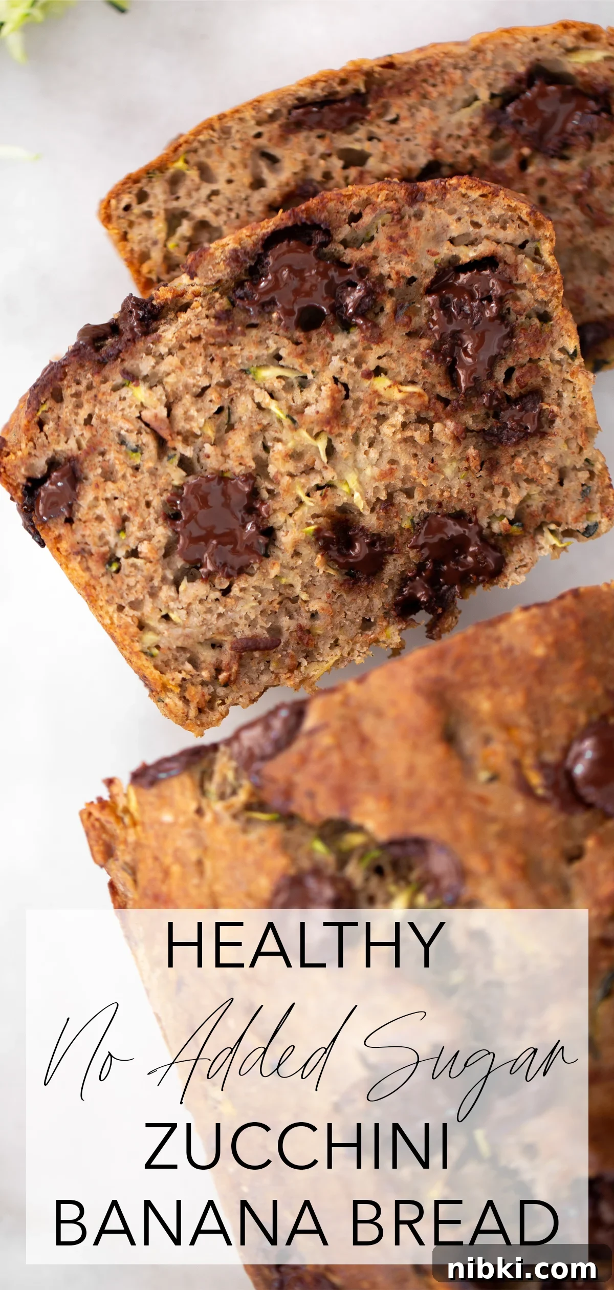 Overhead shot of 2 slices of healthy zucchini banana bread with the rest of the loaf on a white marble background with title text overlay