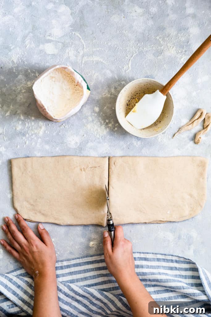 overhead shot of a person using a pizza cutter to slice the dough