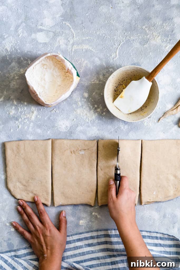 top view of a person slicing the dough with pizza cutter