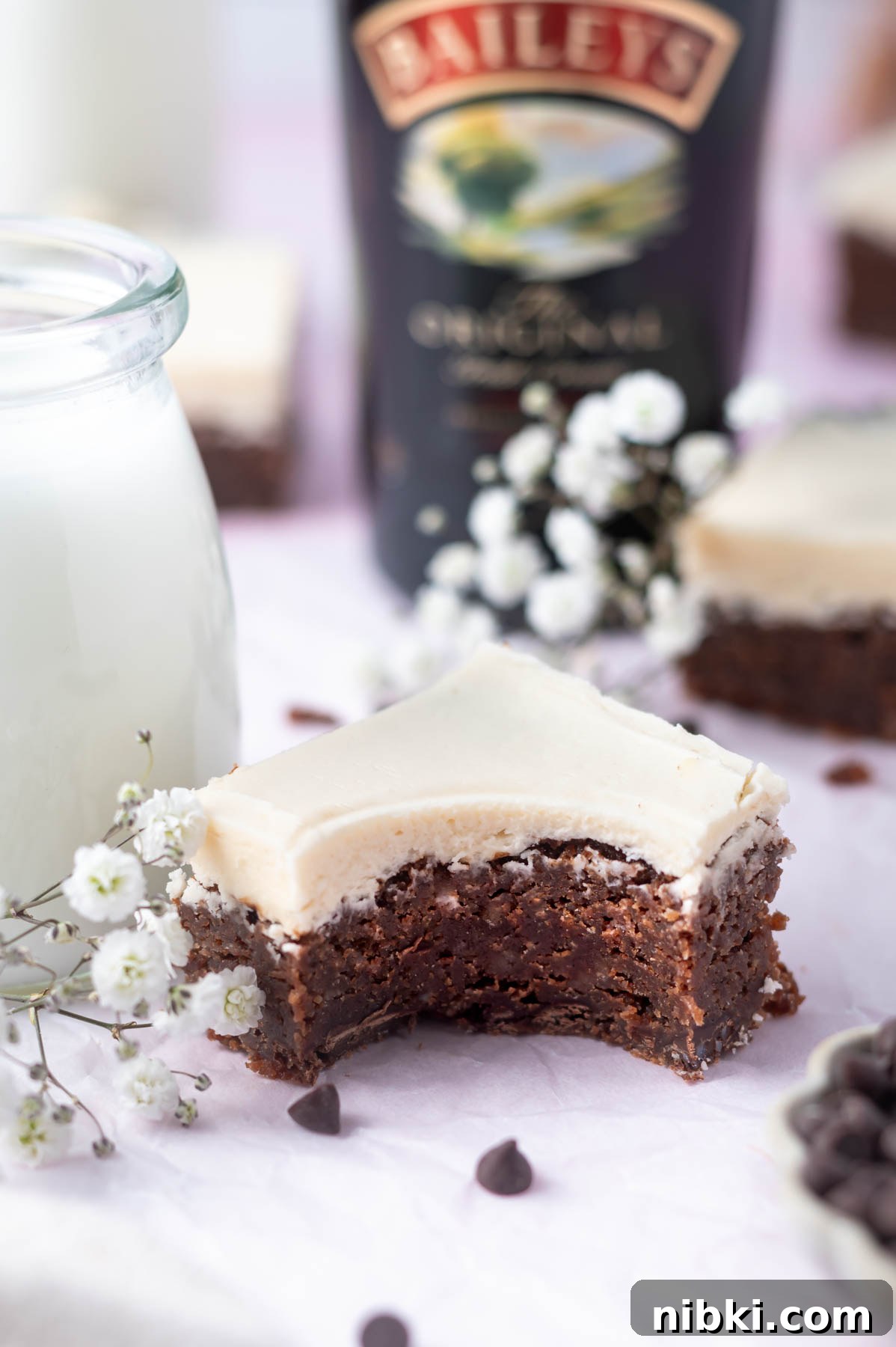 Fudgy Irish Cream Brownies Recipe 11 brownie with a bite missing next to a glass of milk with a bottle of Baileys in the background