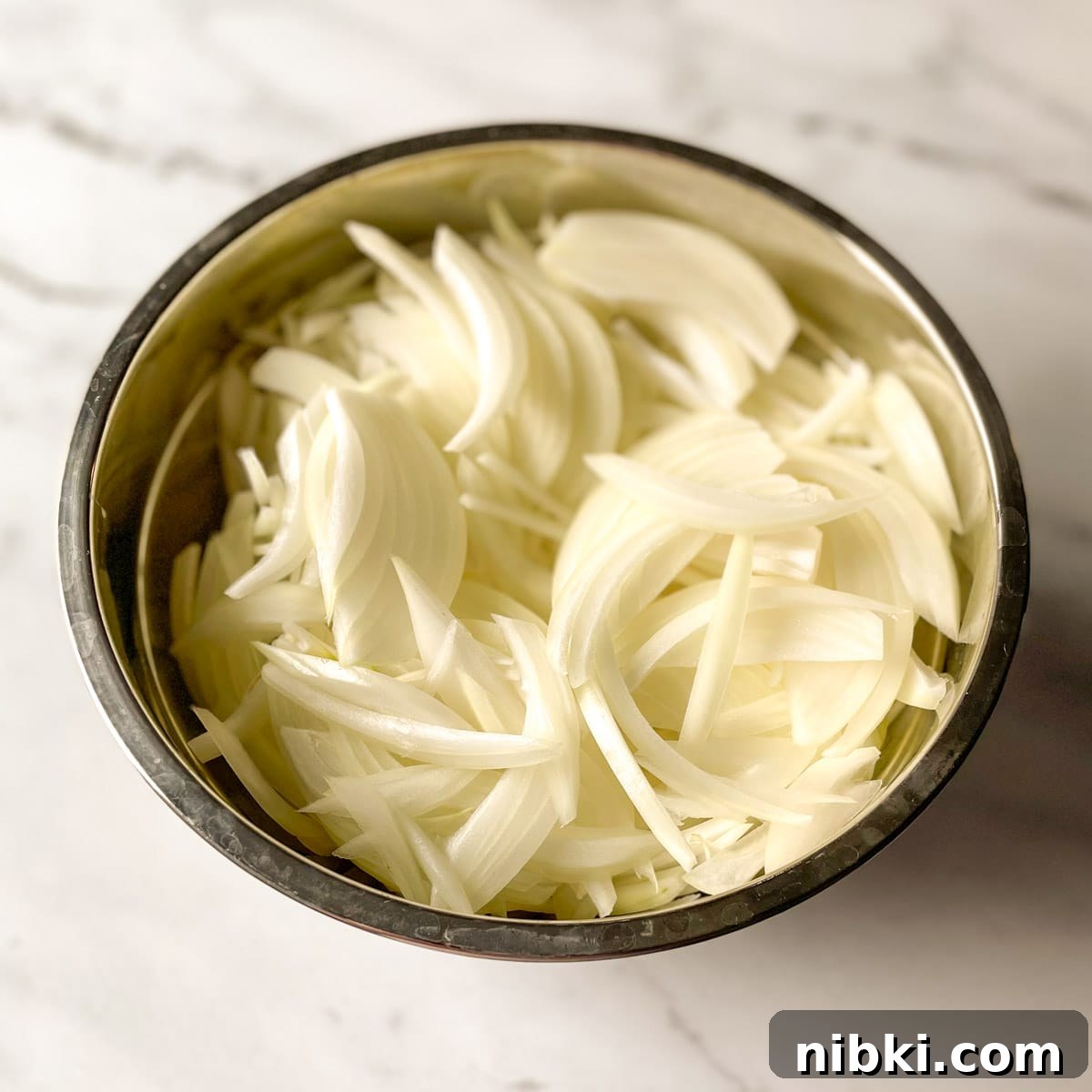 Quick Pickled White Onions for Tacos, Sandwiches and Salads 4 Sliced onions sit in a metal bowl.