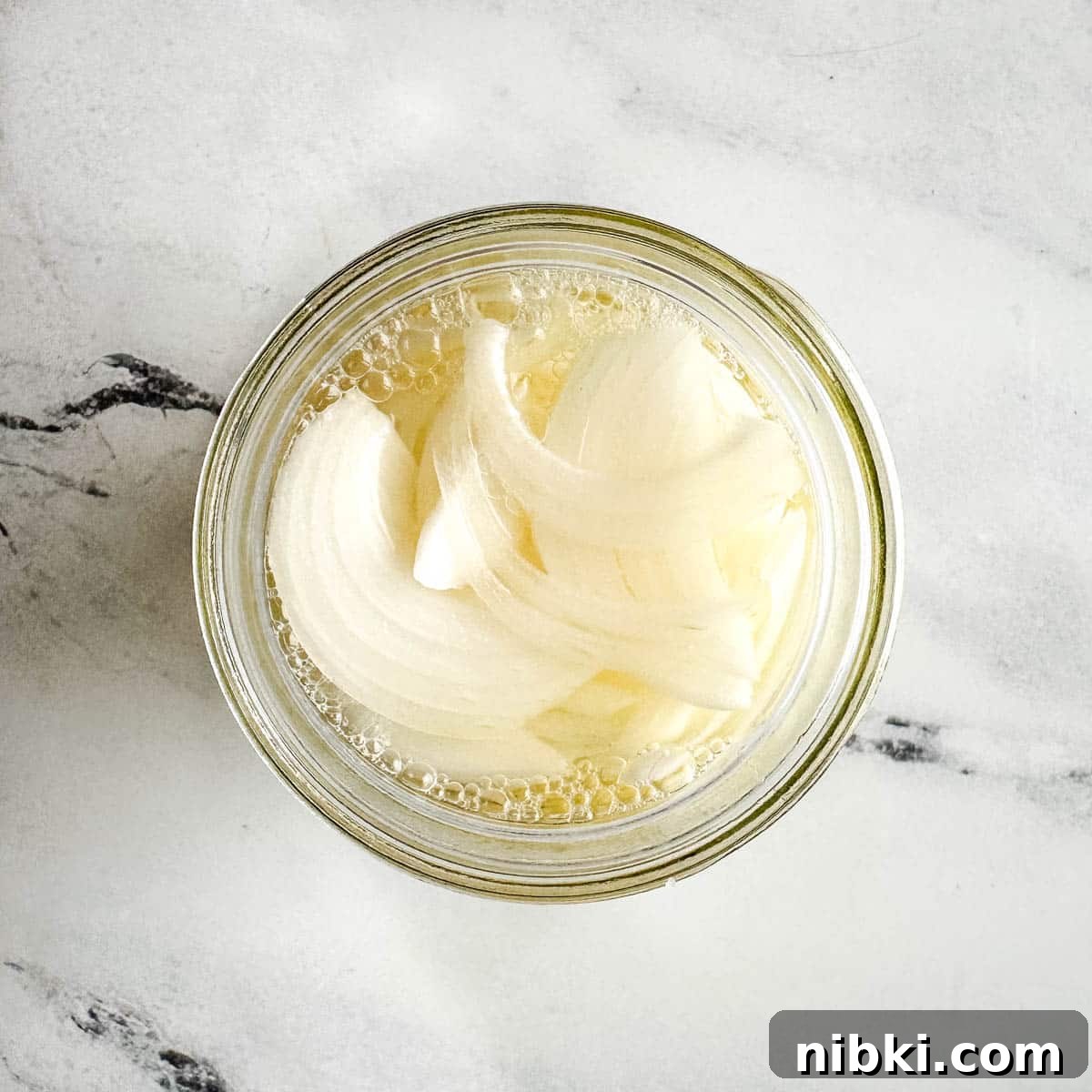 Quick Pickled White Onions for Tacos, Sandwiches and Salads 6 Pickled white onions in a glass jar.