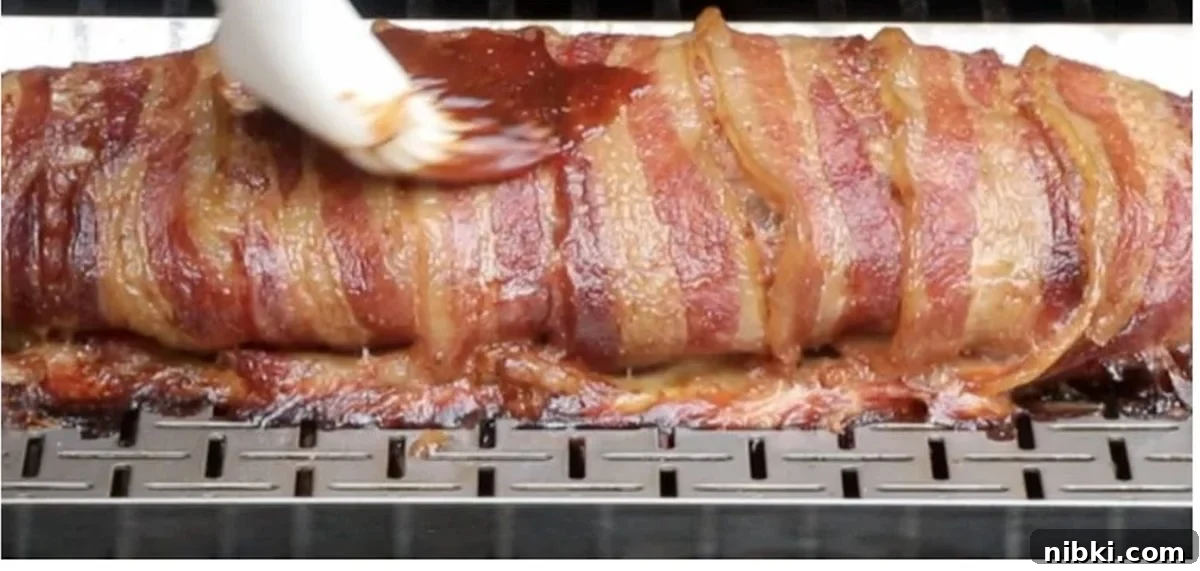 Smoked Meatloaf Recipe with Brown Sugar Glaze 12 Person basting bbq sauce on a meatloaf while it's smoking.