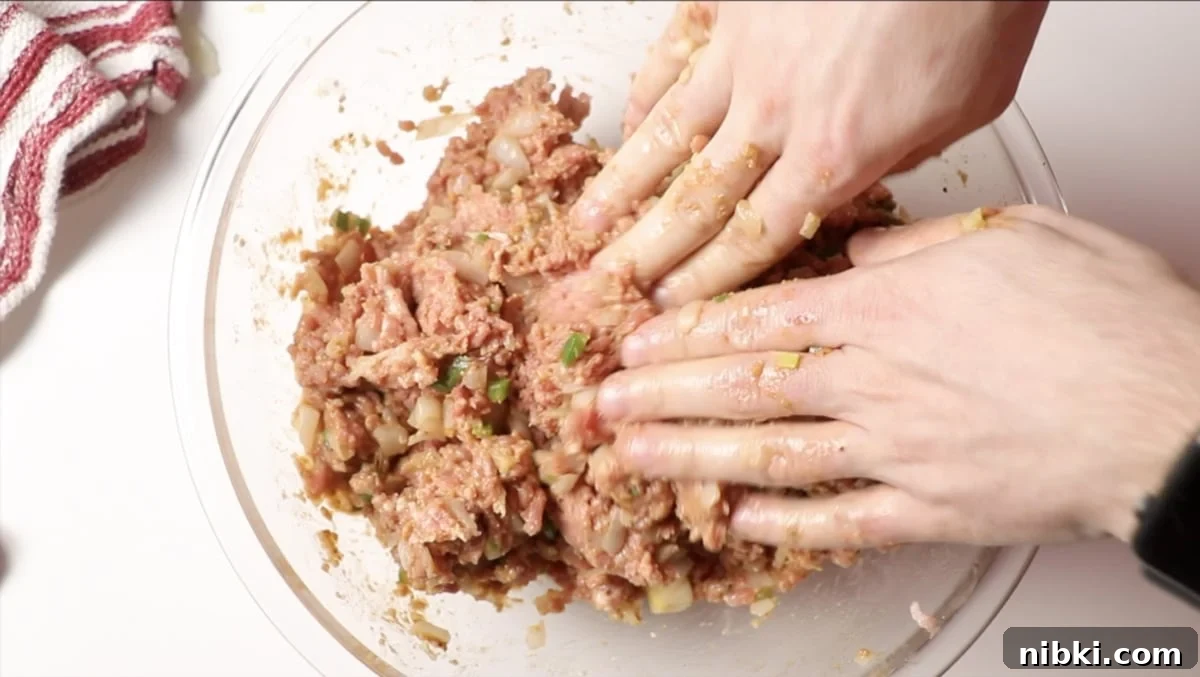 Smoked Meatloaf Recipe with Brown Sugar Glaze 8 Person using hands to mix meatloaf mixture.