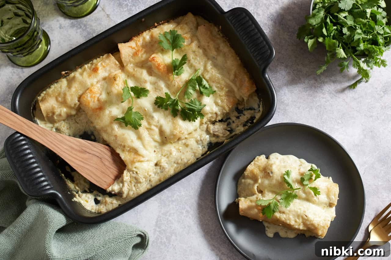 Chicken Enchiladas Suizas: Creamy Tomatillo & Cheese 2 Creamy chicken enchiladas suizas in a black casserole dish topped with cilantro, a black plate with two enchiladas are on the right, gold forks, a bowl of cilantro, two green glasses and a green towel surround the dishes.