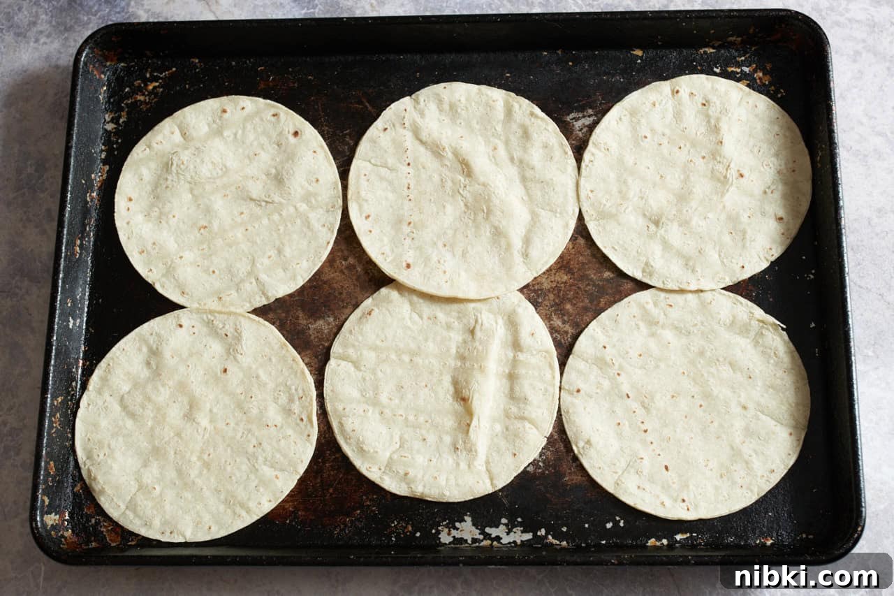 Chicken Enchiladas Suizas: Creamy Tomatillo & Cheese 4 Corn tortillas on a sheet pan.