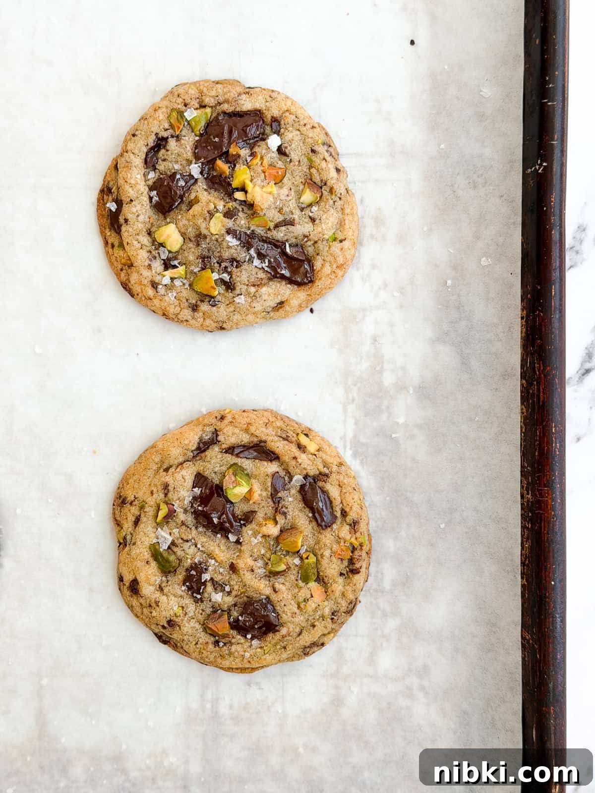 Chewy Pistachio Chocolate Chip Cookies Recipe 10 freshly baked pistachio chocolate chip cookies on a baking sheet.