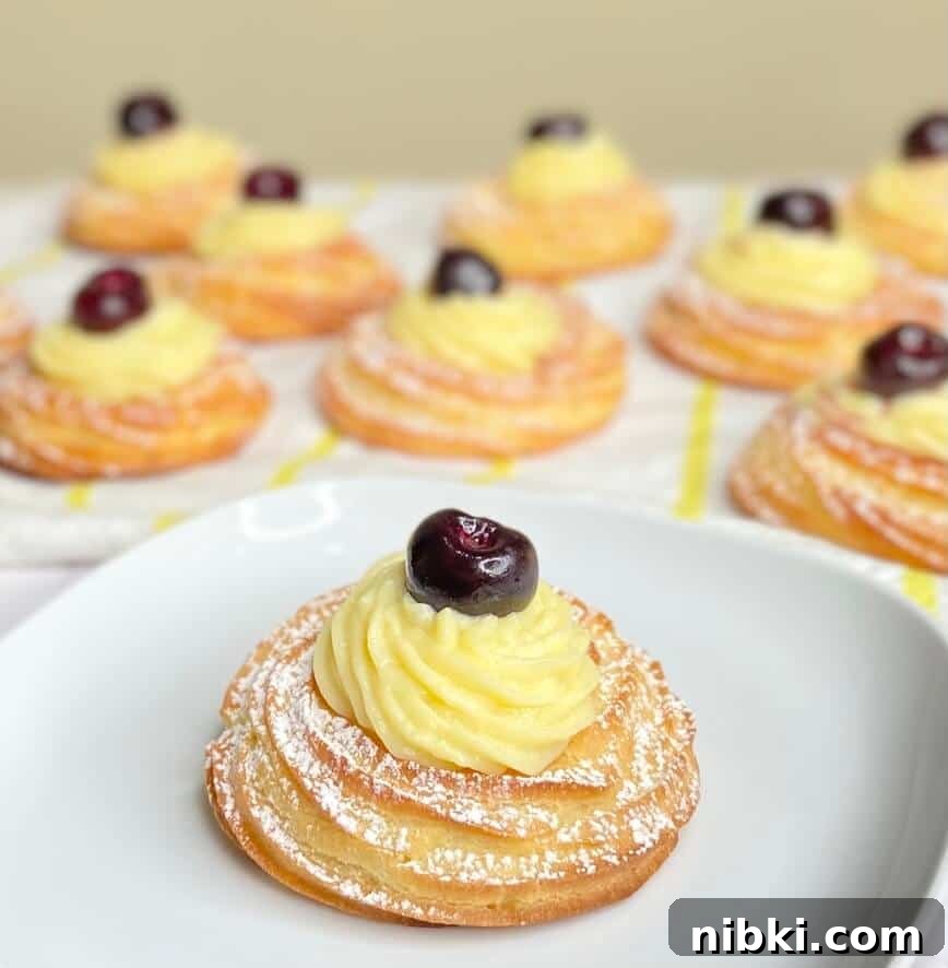 Zeppole di San Giuseppe: Classic St. Joseph's Pastry Recipe 9 Finished pastry filled with cream, a cherry on top, and dusted with powdered sugar.