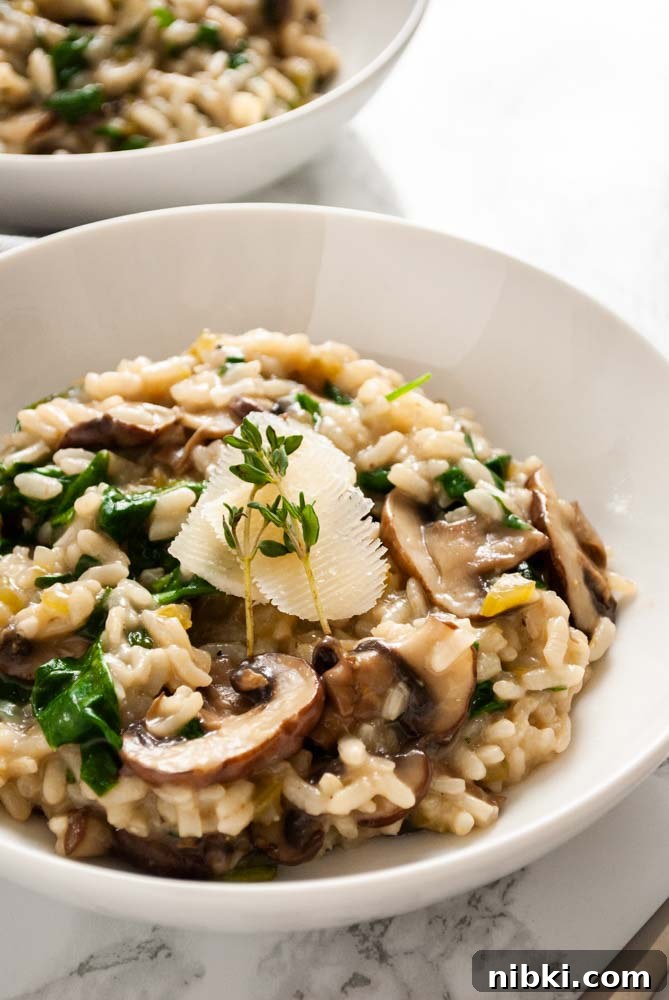 Instant Pot Creamy Mushroom and Spinach Risotto 2 a bowl of spinach and mushroom risotto topped with a sliver of parmesan cheese and thyme sprigs