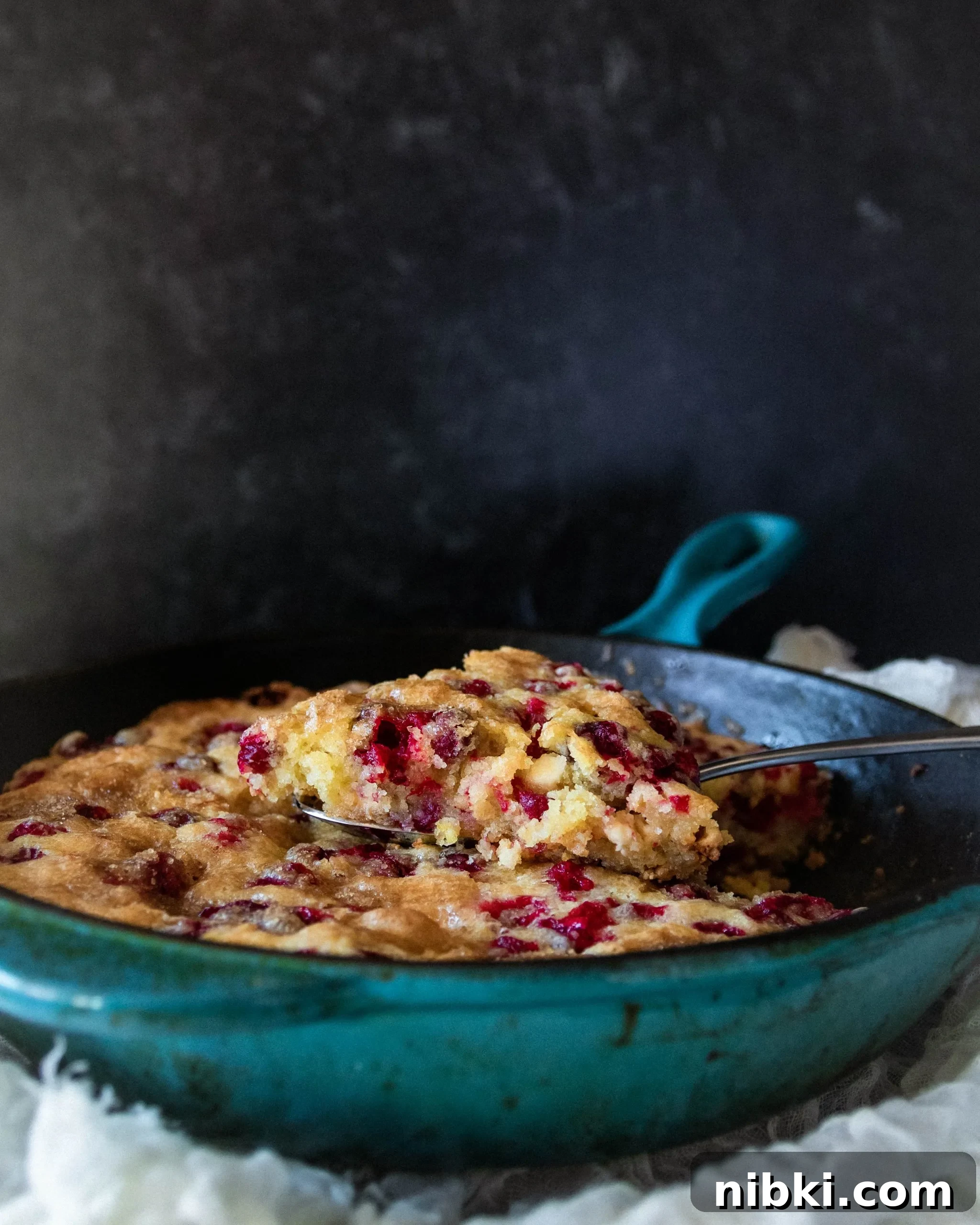 Fresh Cranberry Skillet Cake Recipe 3 slice hovering just above the cast iron skillet cake