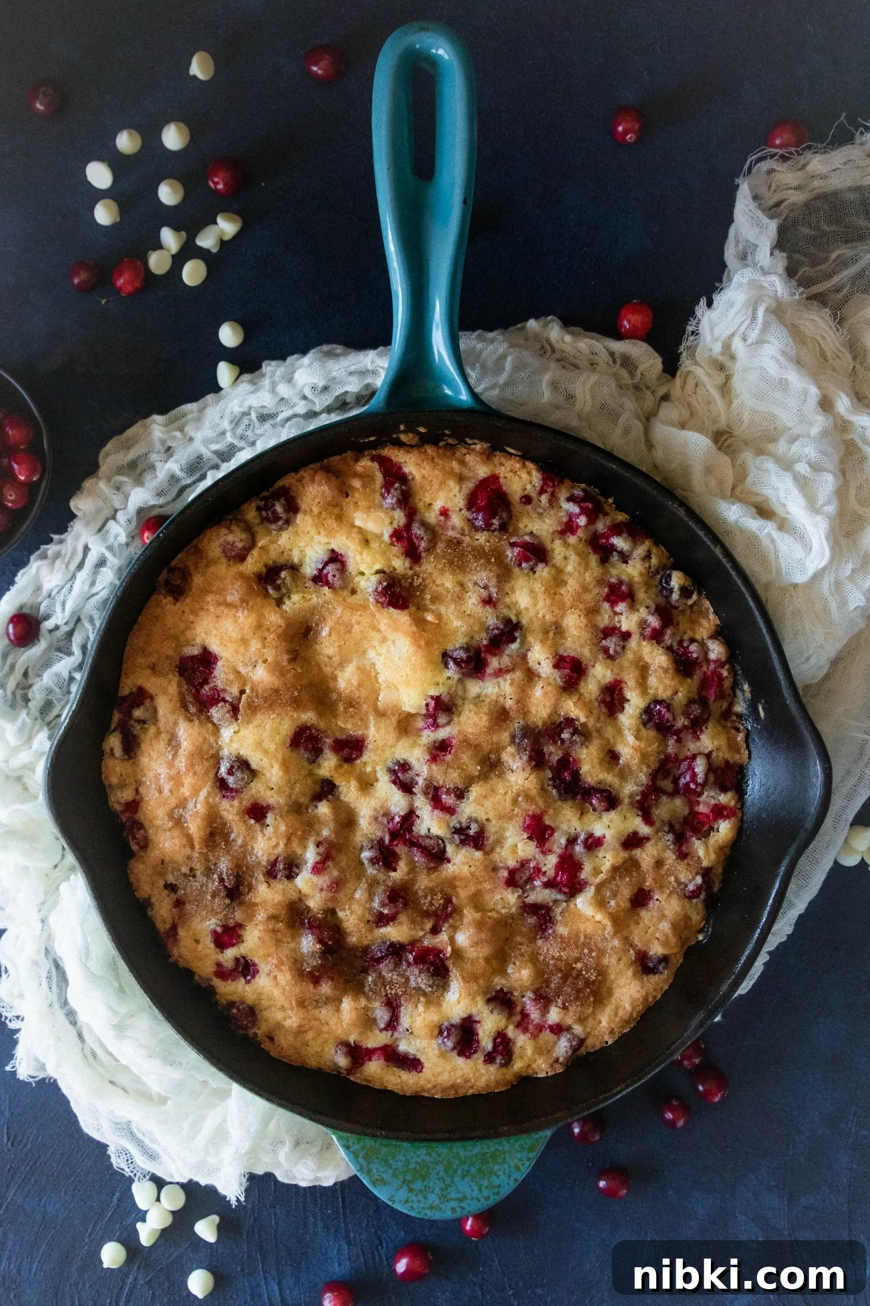 Fresh Cranberry Skillet Cake Recipe 4 top view of the cake in the skillet with scattered cranberries and white chocolate chips