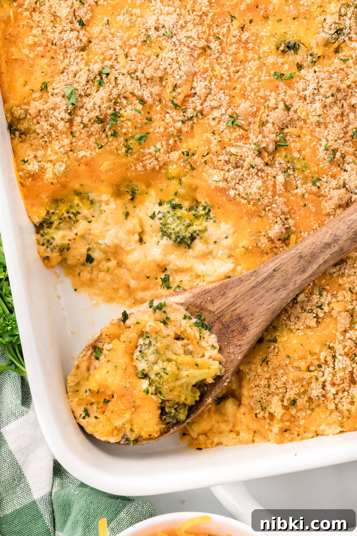 Cheesy Broccoli Rice Casserole in a baking dish with a wooden spoon