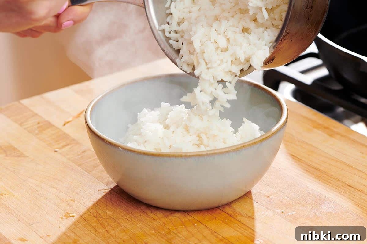 How to Reheat Rice Without Drying It Out 2 Pouring cooked white rice from pan into serving bowl.