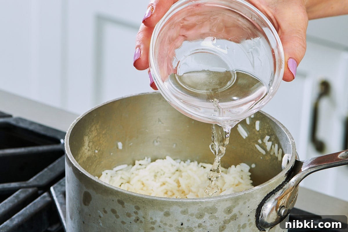 How to Reheat Rice Without Drying It Out 3 Pouring water into pot of leftover cooked rice.