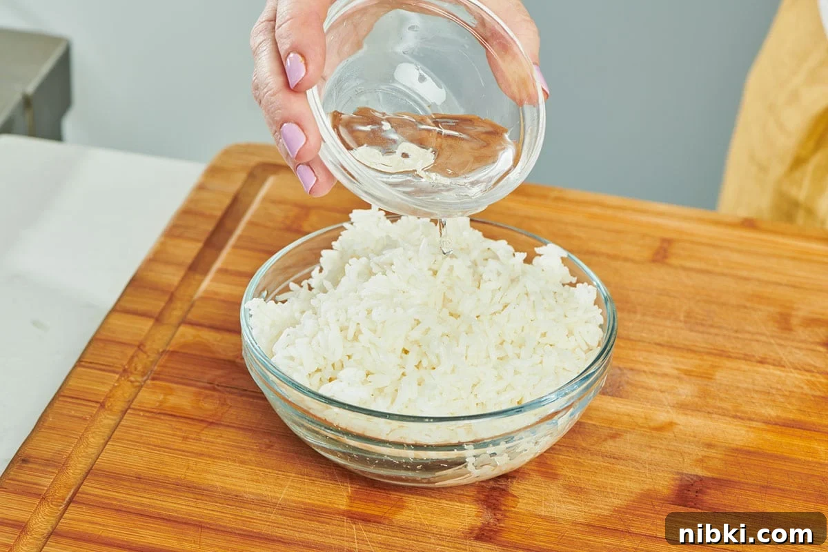 How to Reheat Rice Without Drying It Out 5 Adding water to glass bowl of leftover cooked rice.