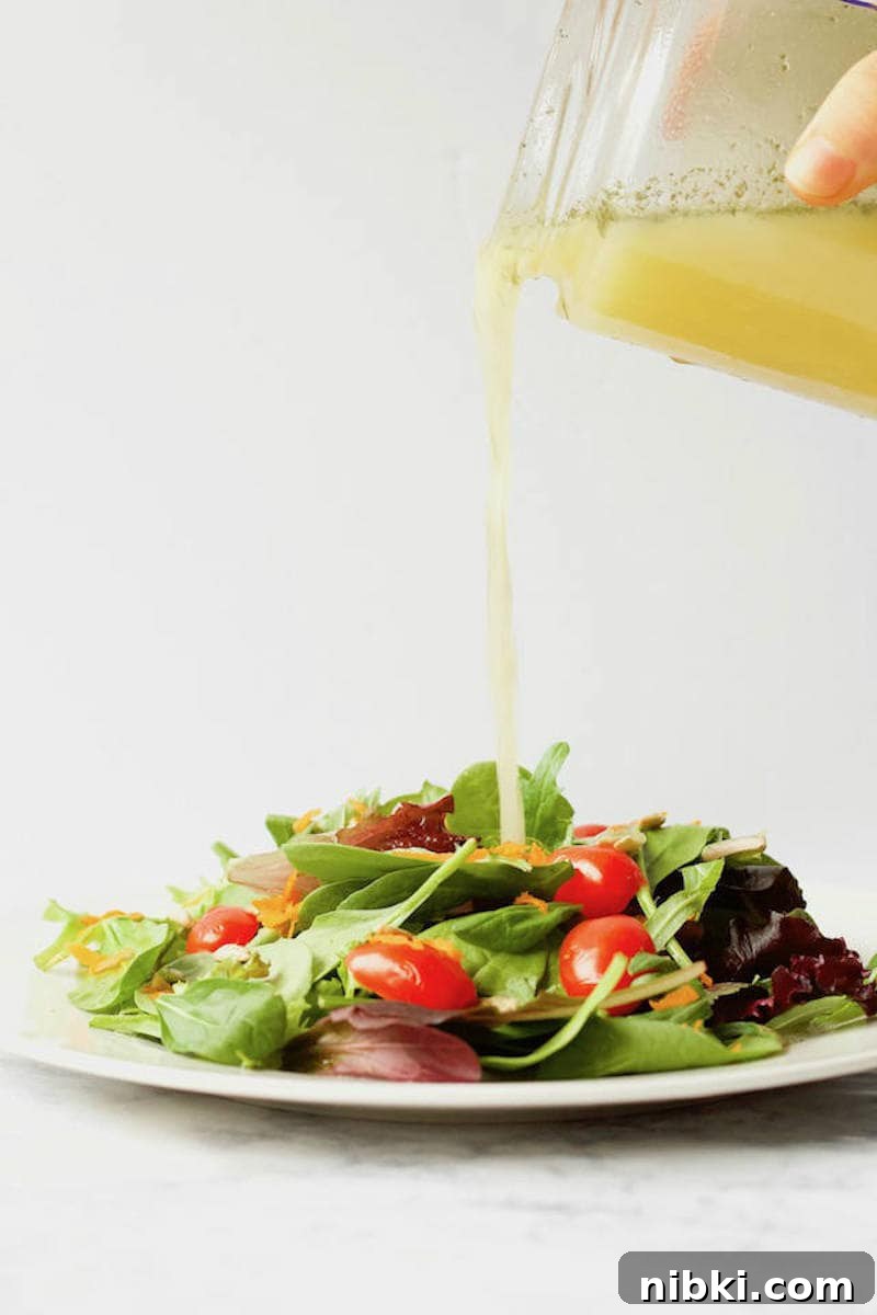 Dill Pickle Vinaigrette Dressing Pouring Over Mixed Green Salad