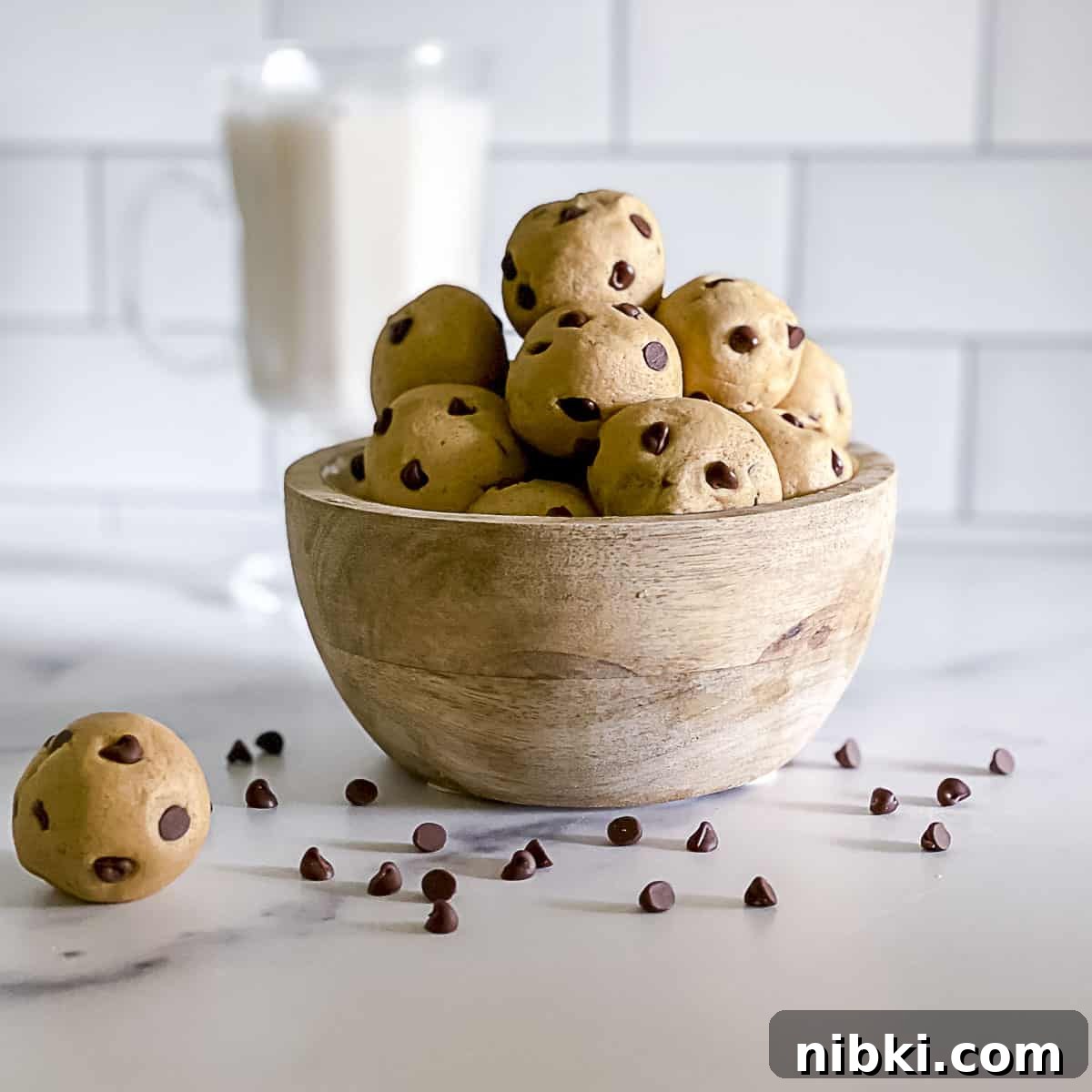 Sweetened Condensed Milk Truffles 11 Edible no bake chocolate chip cookie dough balls stacked in a bowl with chips sprinkled on table.