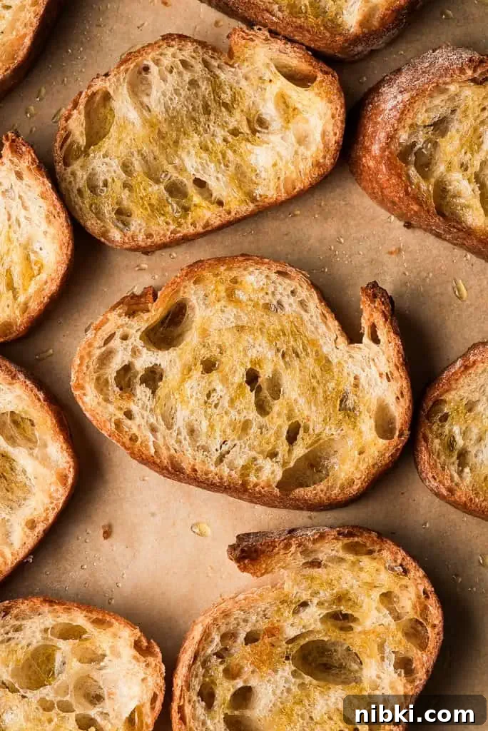 Crostini bread sliced sourdough baguettes drizzled with olive oil on parchment paper