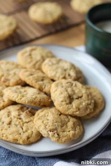 Coconut Pecan cookies on plate with coffee mug of milk.