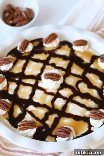 Turtle pie topped with whipped cream and pecans.