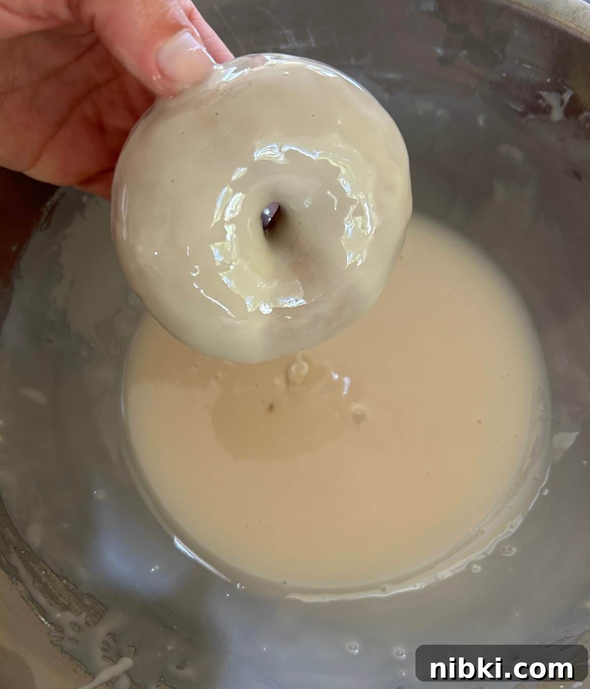 Dipping donut into glaze.