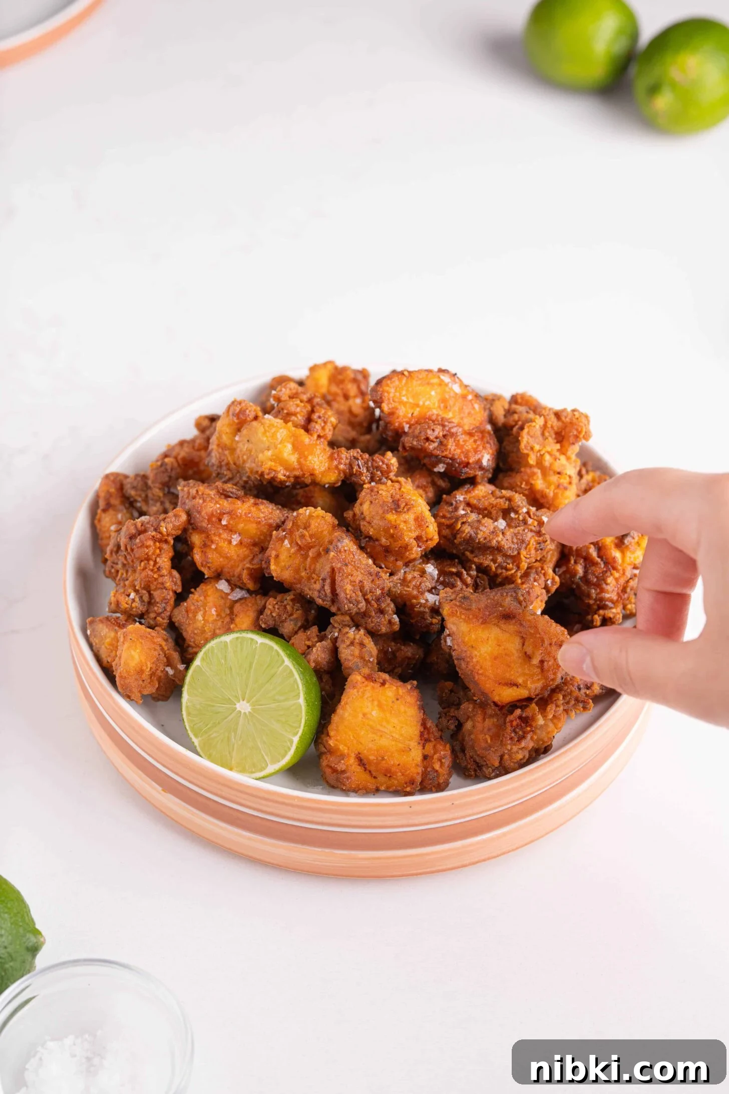 Crispy Puerto Rican Chicken Chicharrones 7 a hand grabbing a piece of Puerto Rican chicken
