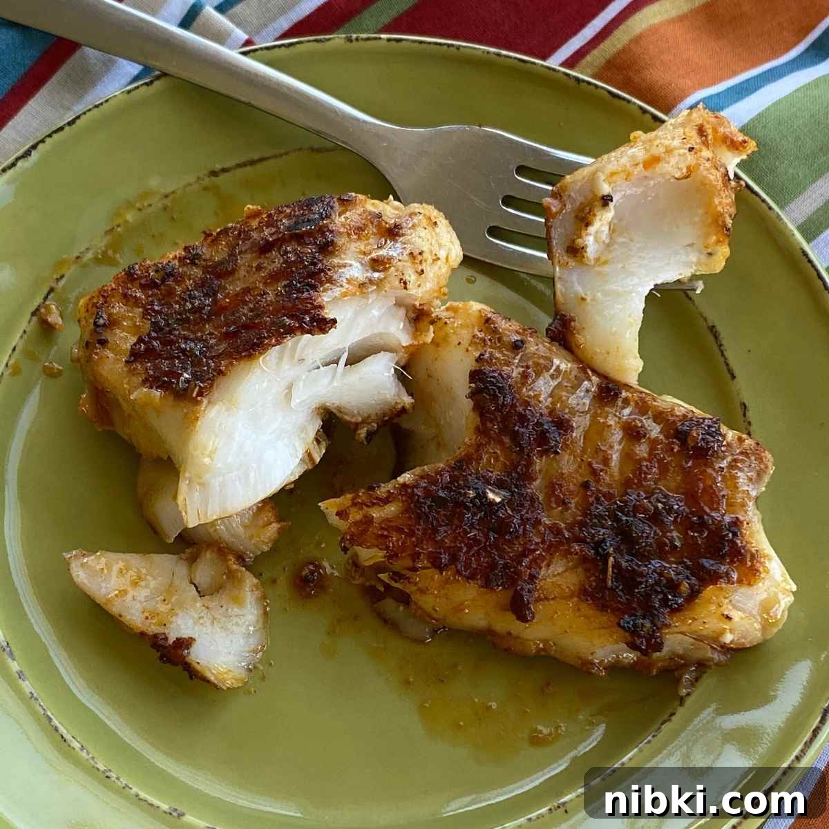 Blackened cod fillet on a plate showing flaky white flesh.