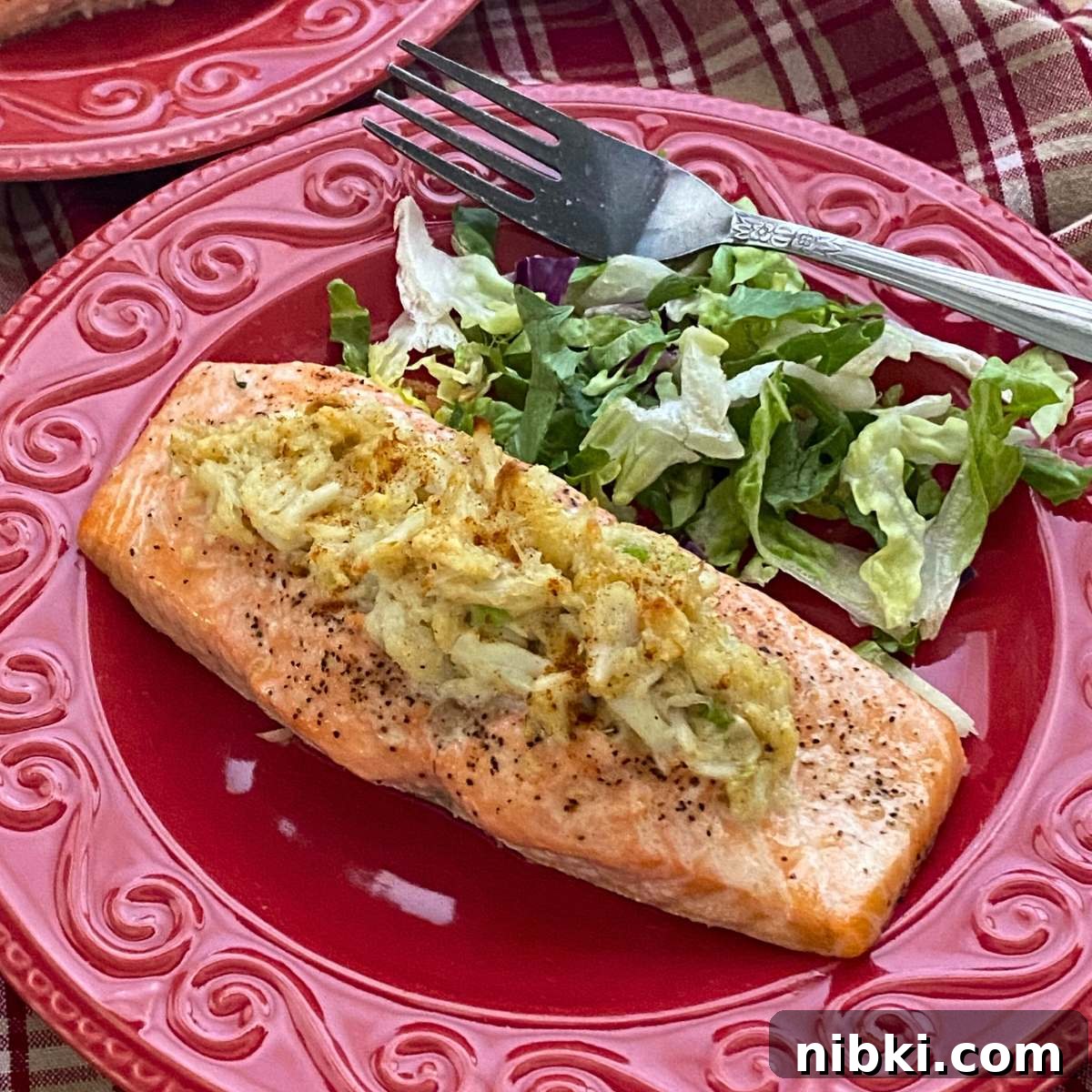 Crab stuffed salmon on a plate with salad and fork.