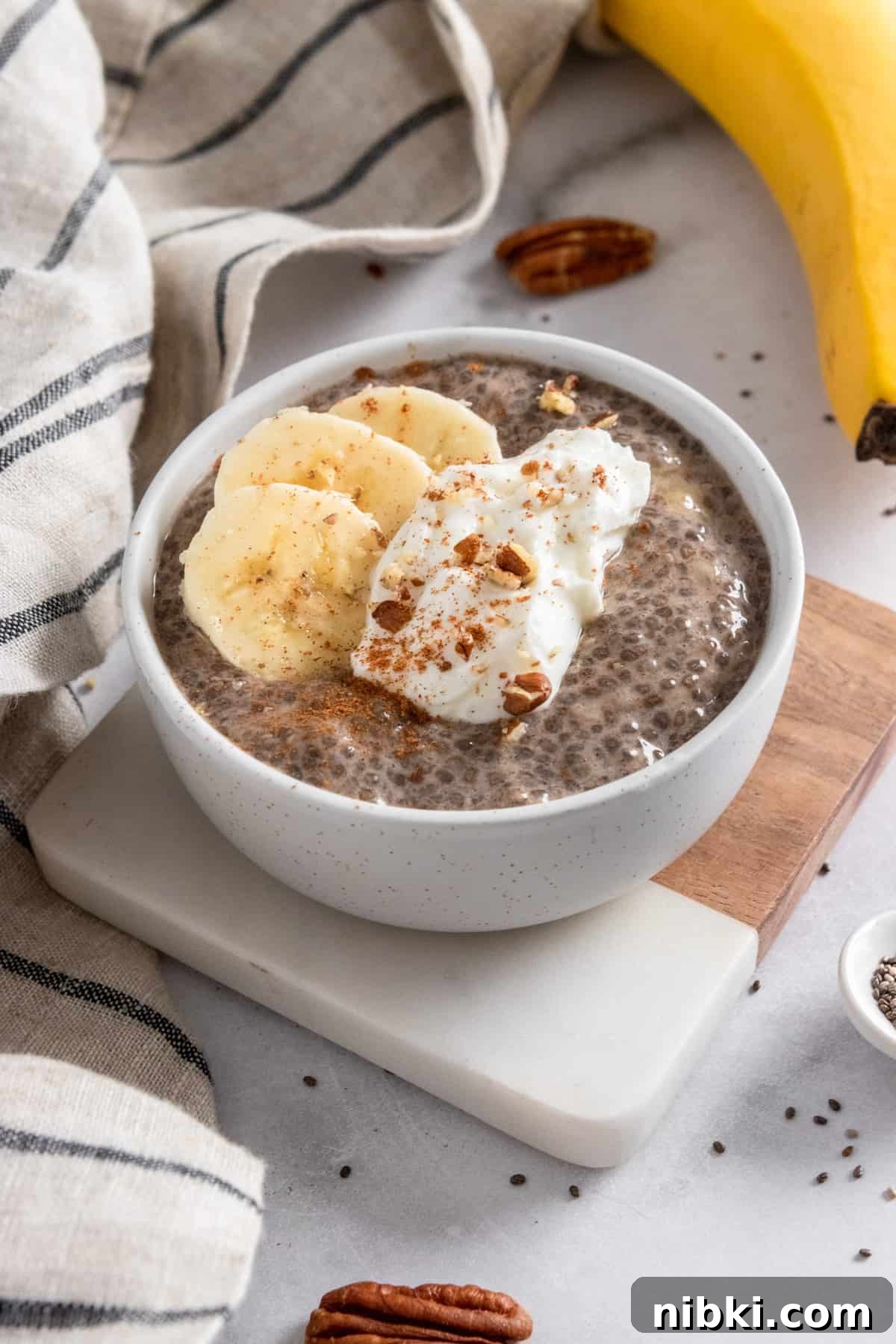 Banana chia seed pudding in bowl with dollop of yogurt, banana slices and cinnamon on top.